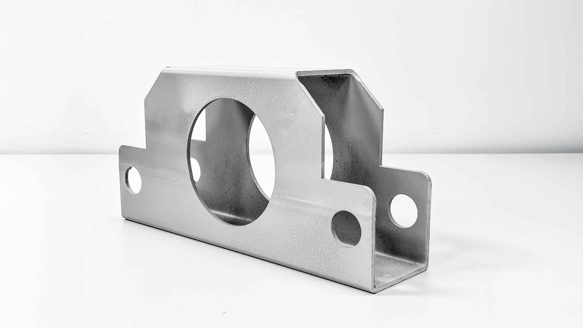 Peça retangular tubular usinada com grande abertura circular central, demonstrando corte e fabricação de precisão.