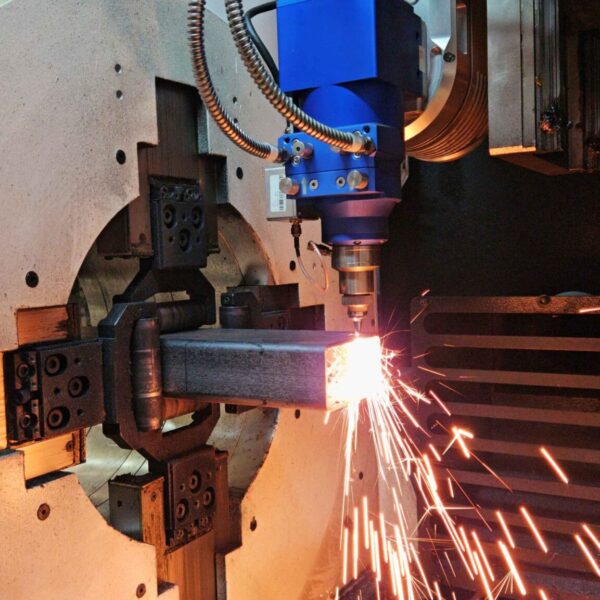 Máquina industrial realizando um corte a laser em um tubo de aço retangular com alta precisão e intensa geração de faíscas.